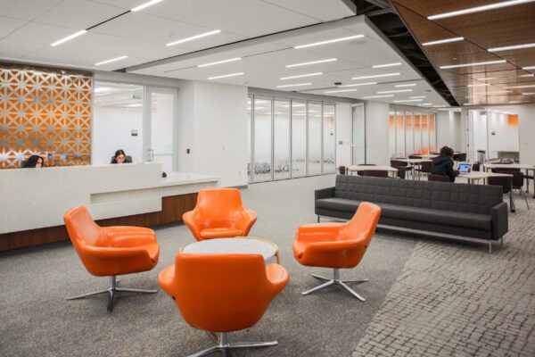 Table with orange chairs in a room with couches