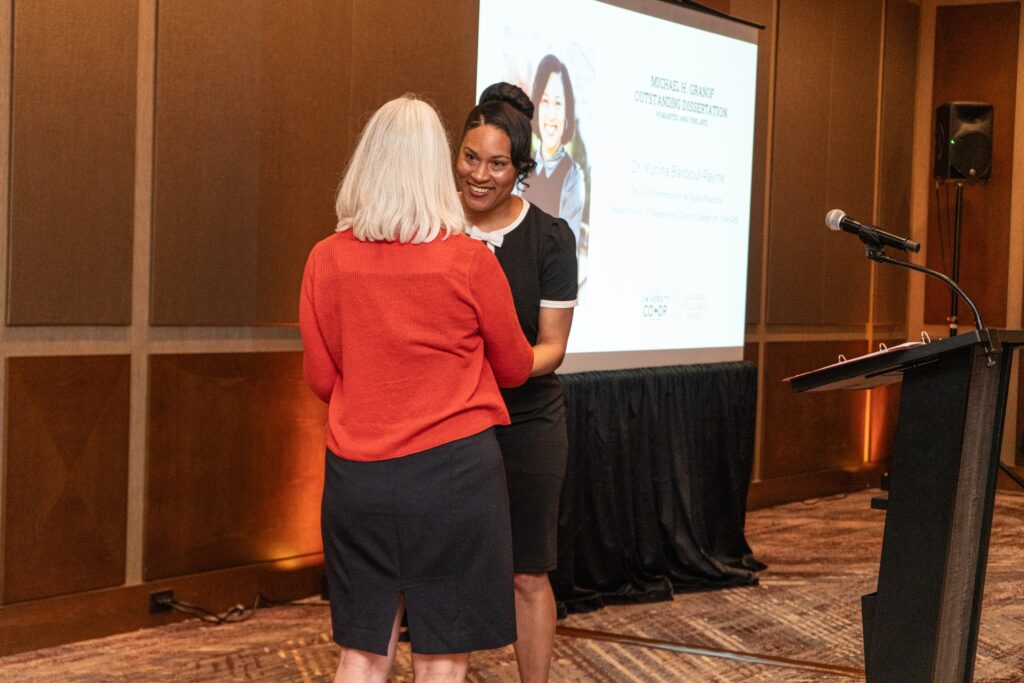 Woman receiving an award and shaking another woman's hand