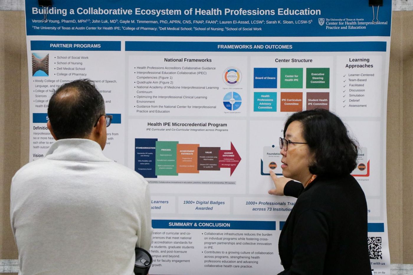 Two attendees discussing a research poster