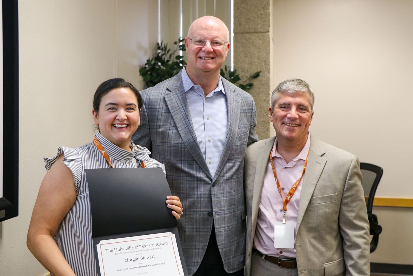 Award recipient with two colleagues holding a certificate